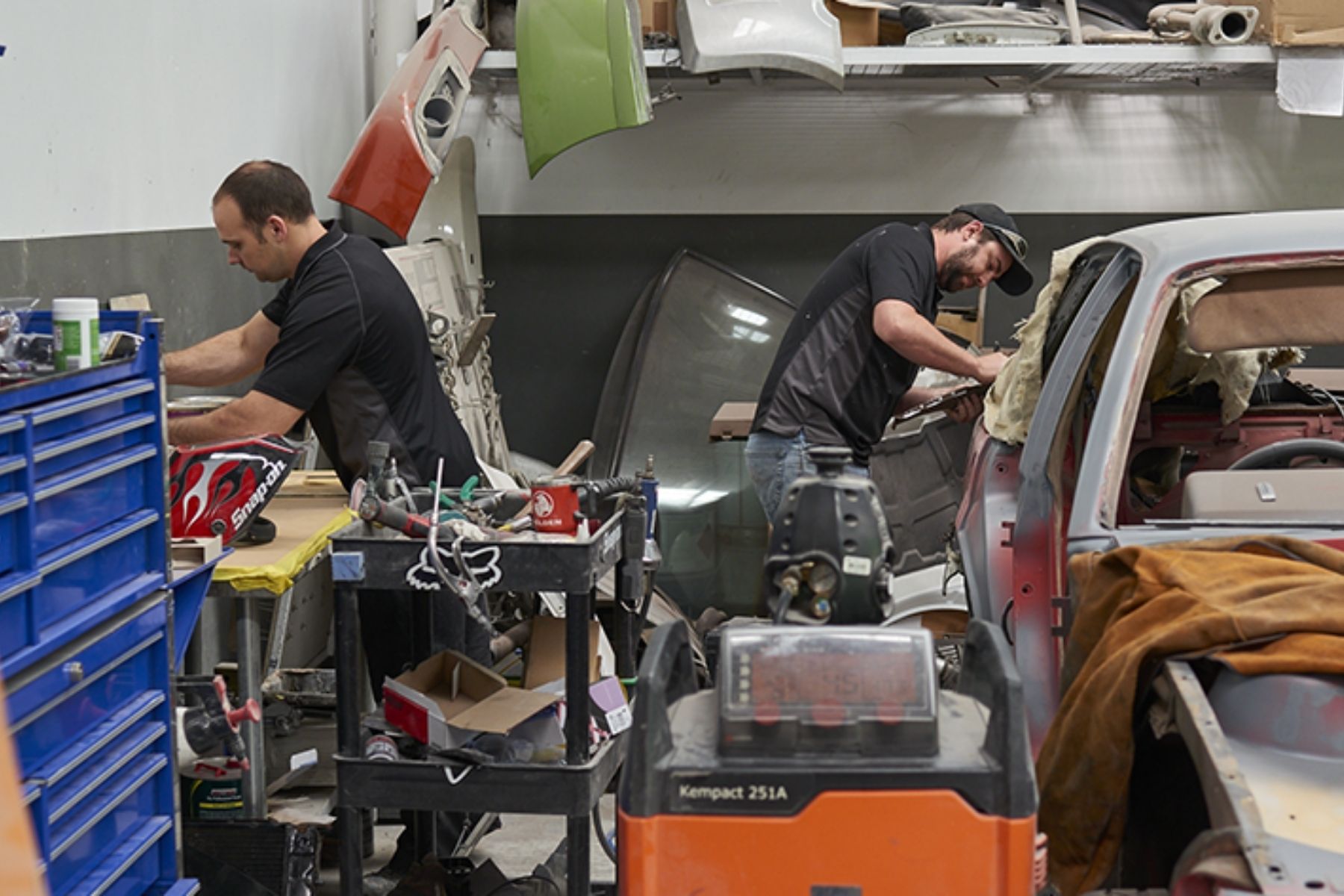 Photo of mechanics at work in a workshop, surrounded by equipment and tools.