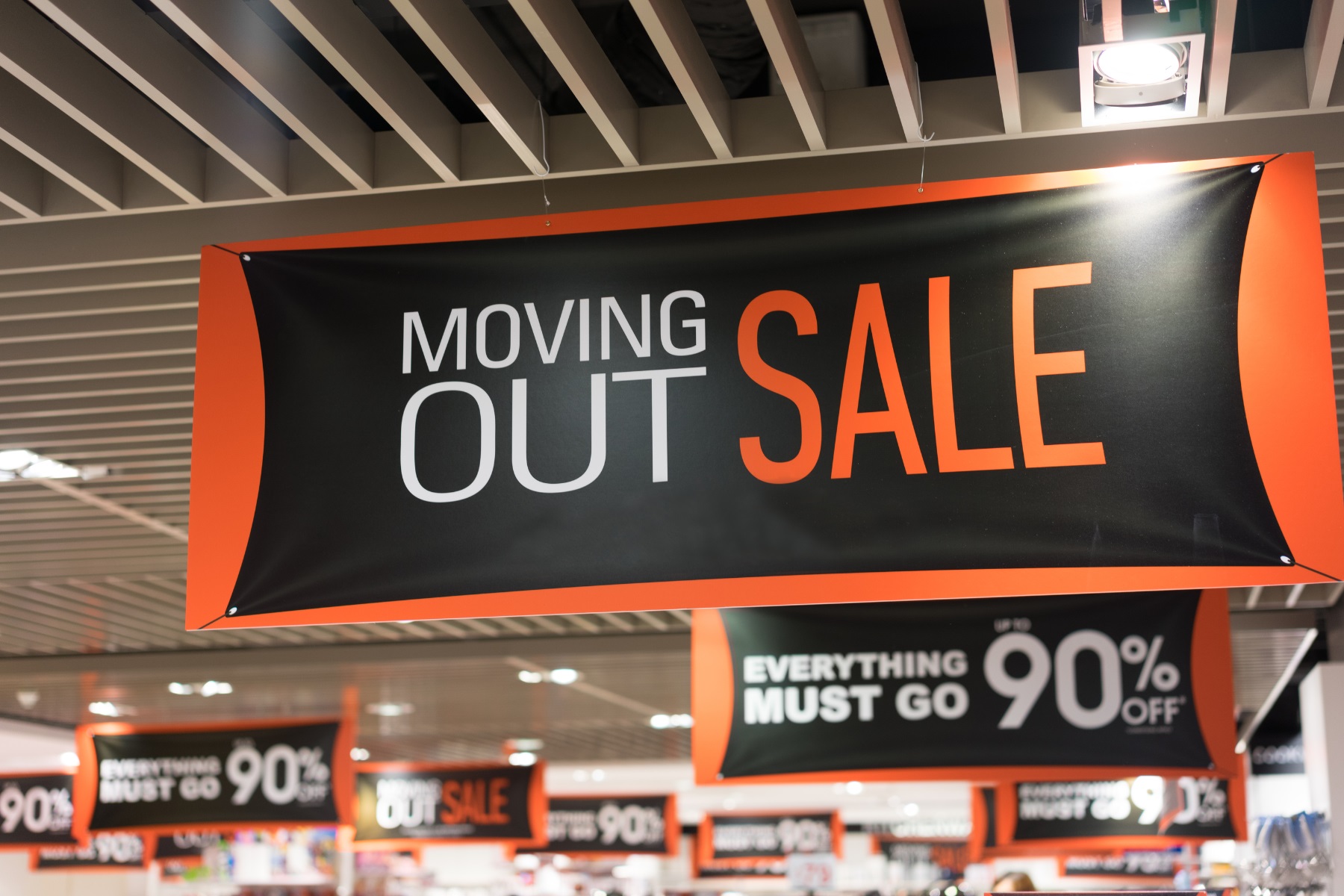 Photo of a banner hanging in a retail store. The banner has 'Moving out sale" printed on it.