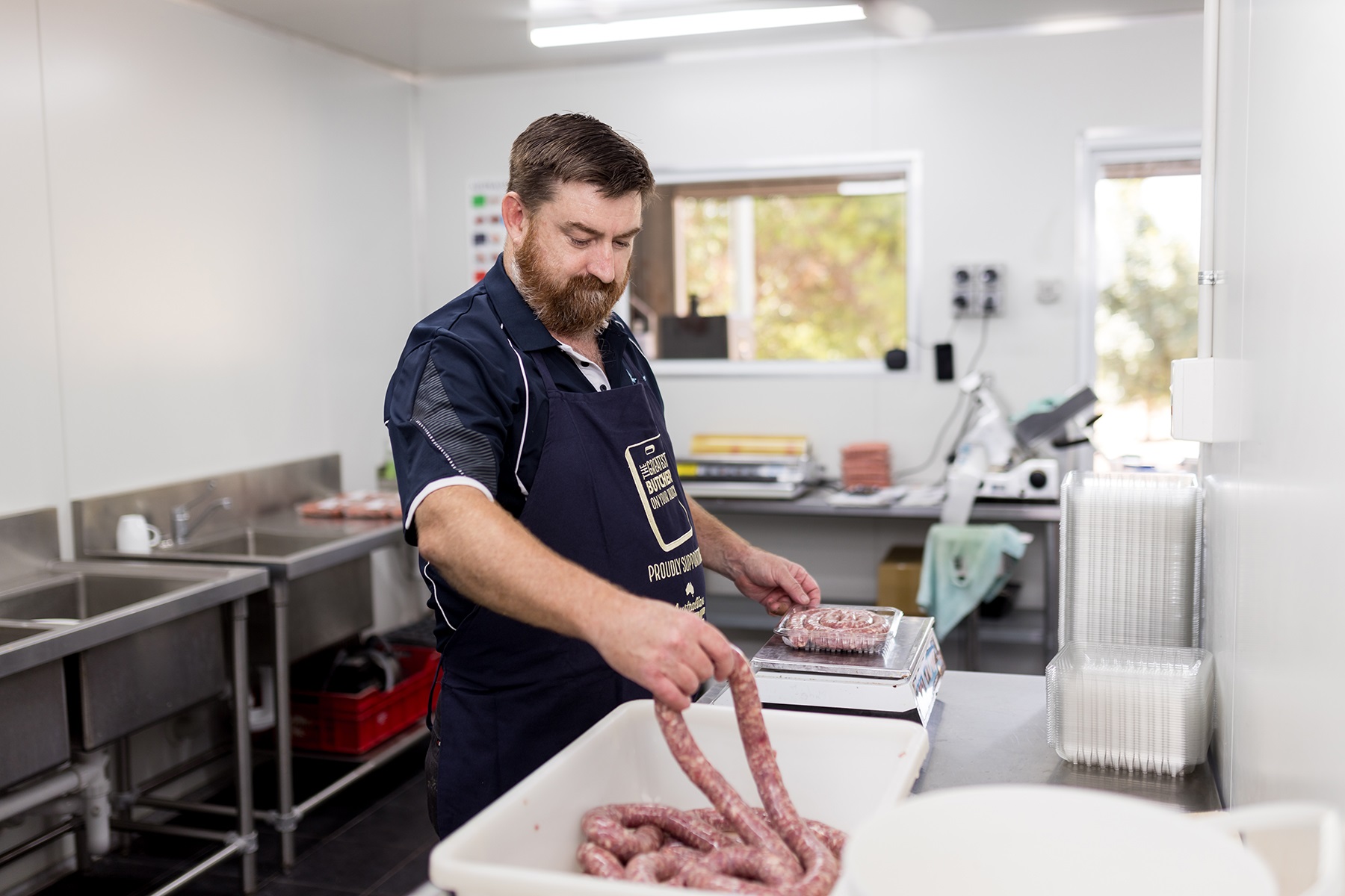 Photo of a male butcher making sausages.